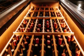 Bouteilles couchées sur des clayettes en bois dans une cave à vin